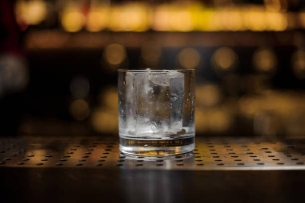 istock Glass with big ice cube standing on the bar stand 1078043836