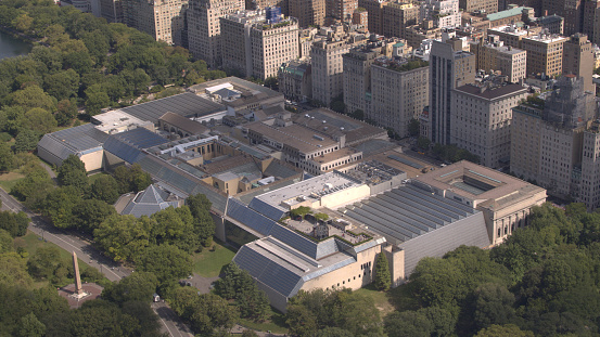 AERIAL: Flying above Upper East side overlooking lush green Central Park along the 5th Avenue in sunny New York City. Luxury condominium apartment buildings with Central Park view and MET museum