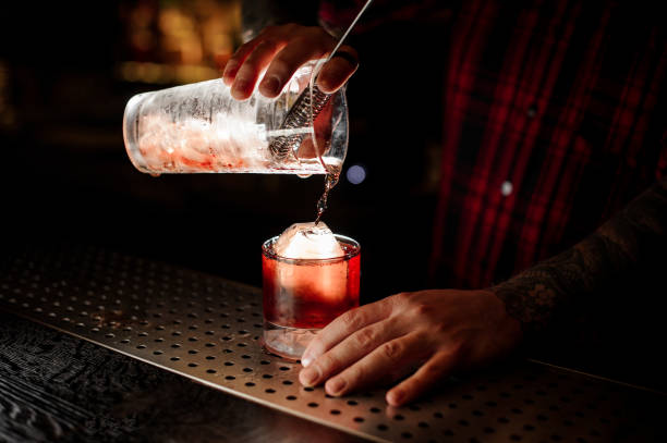 barista versando un delizioso cocktail boulevardier dalla tazza di misura - cocktail transparent cocktail shaker glass foto e immagini stock