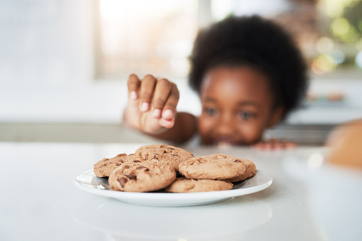 Cropped shot of an adorable little girl stealing cookies at home