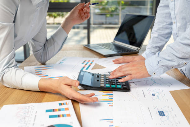 istock Cropped profile side view two person in formal wear stand vs behind desktop table in loft interior communicate try find best decision calculate invoice blank learn trade information 1078060158