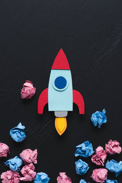 istock cardboard rocket with pink and blue crumpled paper balls on black background, setting goals concept 1078060416