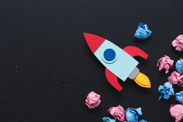 istock cardboard rocket with crumpled paper balls and copy space on black background, setting goals concept 1078060474