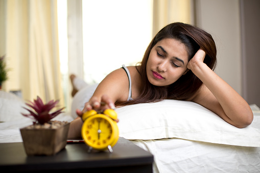 Woman reaching out for alarm clock