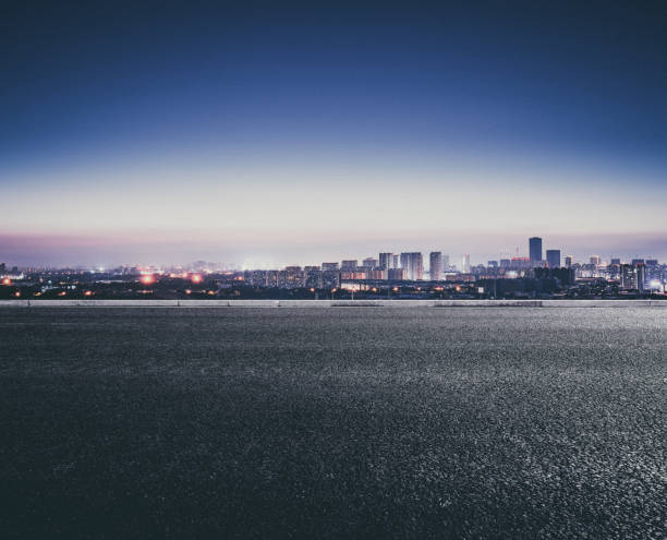 una città lontana dalla strada dopo che il sole tramonta la sera - downtown district skyline skyscraper asphalt foto e immagini stock