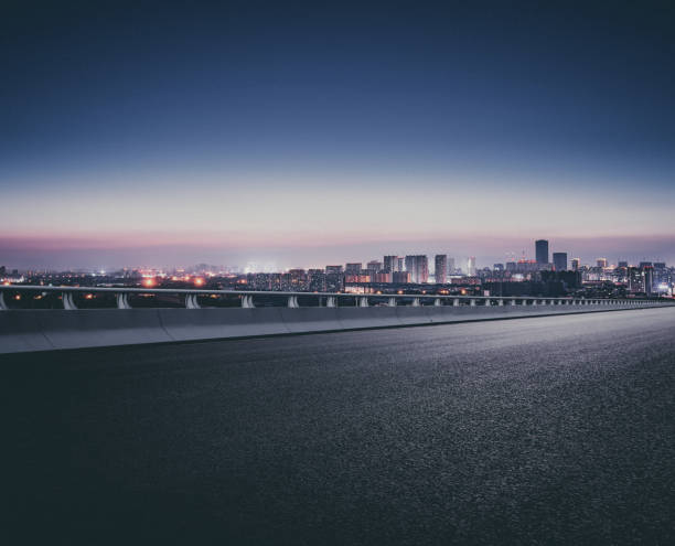 una ciudad muy lejos de la carretera después de la puesta del sol en la noche - urban road fotografías e imágenes de stock