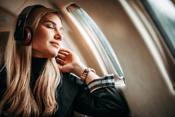 hermosa mujer joven escuchando música con los auriculares en un jet privado - status symbol audio fotografías e imágenes de stock