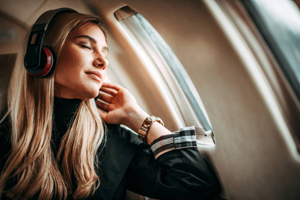 belle jeune femme écoutant de la musique via le casque dans un jet privé - status symbol audio photos et images de collection