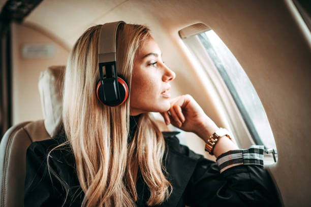 hermosa mujer joven escuchando música con los auriculares en un jet privado - status symbol audio fotografías e imágenes de stock
