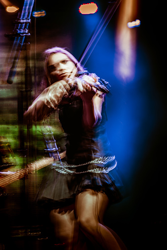 Woman playing violin on rock koncert. Blurred motion.