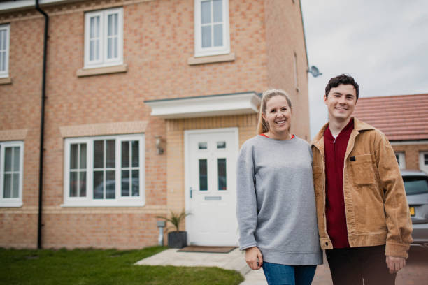 Couple Standing Outside New Home A wide-view shot of a young couple standing outside their new home, they have wide smiles on their faces. in front of stock pictures, royalty-free photos & images