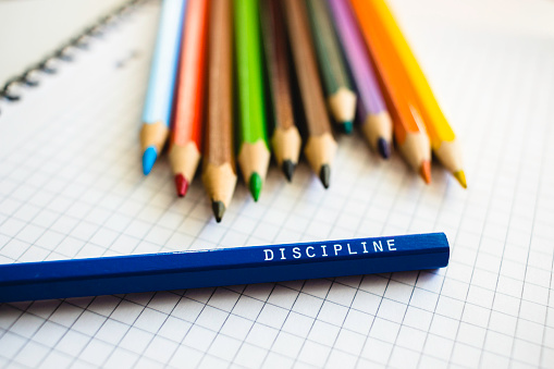 Discipline word on a pencil. School stationery, colored pencils, motivation, achievement, practice, education concept