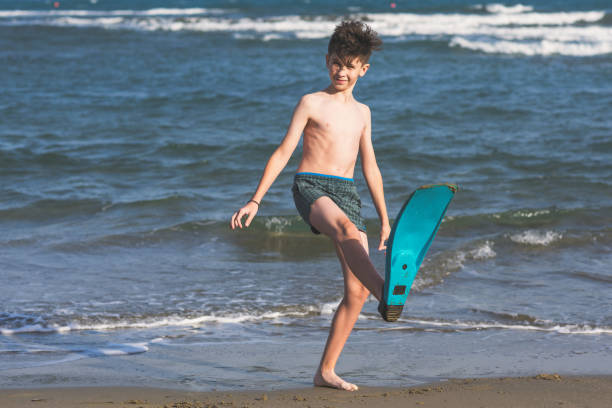 szczęśliwy nastolatek chłopiec w płetwy pływać zabawy na piasku оn na plaży podczas wakacji - underwater mine zdjęcia i obrazy z banku zdjęć