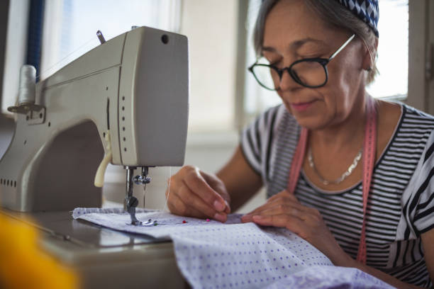 Woman working at the sewing machine at home Senior woman working at the sewing machine at home woman tailor stock pictures, royalty-free photos & images