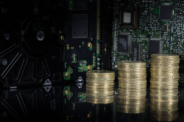 istock Stacked gold coins (UK Sterling GBP £2 coins) on a reflective background with circuit board / hard drives background. 1078088340