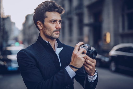 Handsome stylish guy using camera on the street looking away