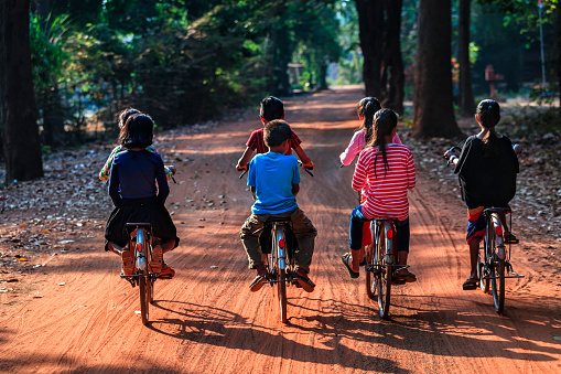 Happy Cambodian children riding bicycles in village near Siem Reap, Cambodia