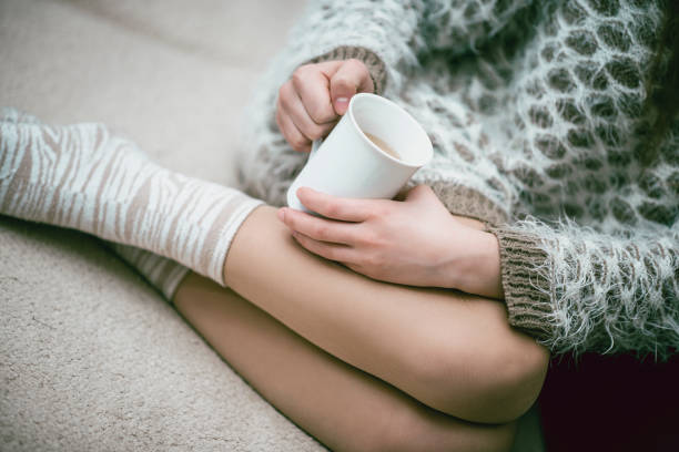 istock Female Wearing Sweater and Drinking Tea On Sofa 1078107816