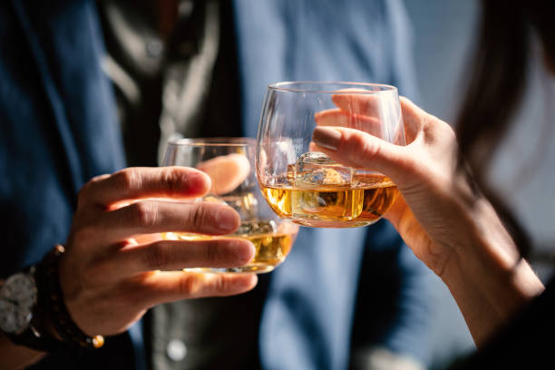 Man and woman celebrating with whiskey glasses Man and woman celebrating with whiskey glasses whiskey photos stock pictures, royalty-free photos & images