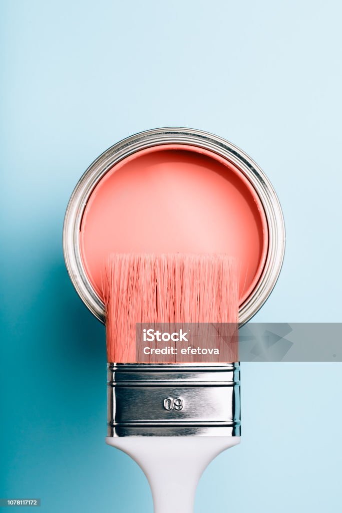 Brush on open can of Living Coral paint on blue pastel background Brush with white handle on open can of Living Coral paint on blue pastel background. Color of the year 2019. Main trend concept. Paint Stock Photo