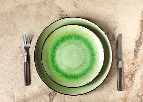 Two Green Empty Round Plates with Fork and Knife, Top View. Table Setting
