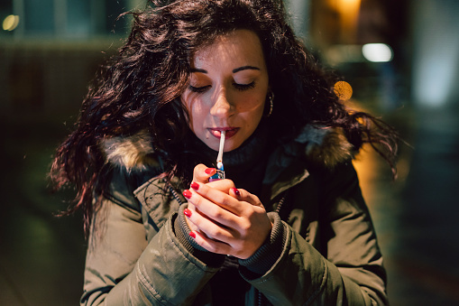 Young Adult Woman Lighting Cigarette In The City At Night