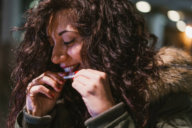 giovane donna adulta che rotola una sigaretta all'aperto in città di notte - cigarette wrapping foto e immagini stock