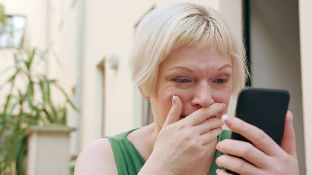 istock Young Blonde Woman Sitting Outside and Using Phone 1078125956
