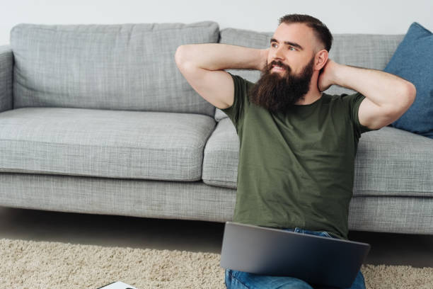 istock Bearded man relaxing on carpet with laptop 1078129448