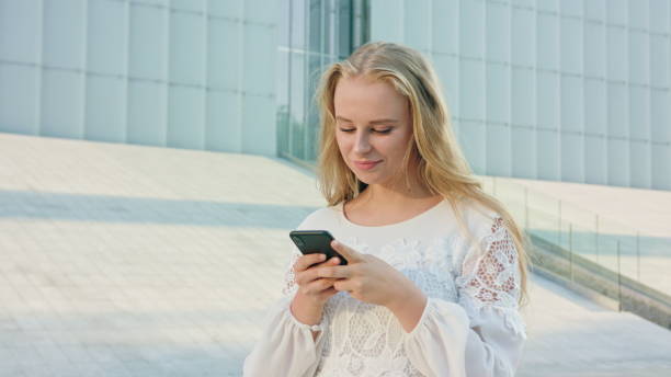 istock Young Blonde Lady Walking and Using a Phone in Town 1078130988