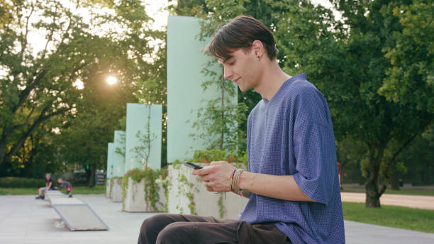 istock Young Man Sitting and Using a Phone in Town 1078141584