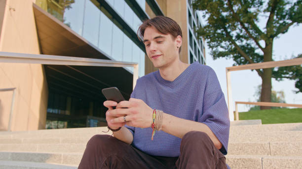 istock Young Man Sitting and Using a Phone in Town 1078141862
