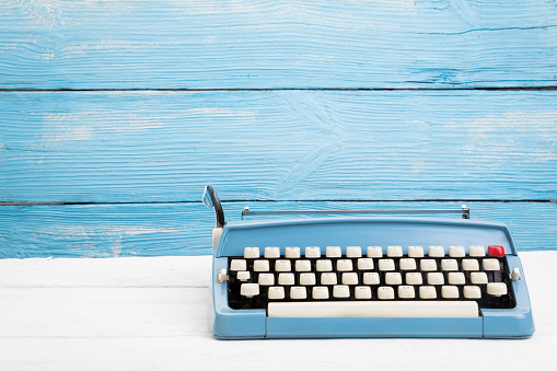 Vintage typewriter on wooden blue background with space on text