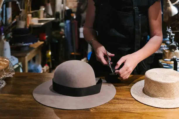 Milliner making handmade customized hats in her workshop.