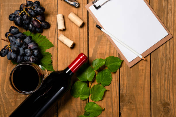 istock Composition with bottle and glass of wine with grape bunch and vine leaves and notepad on wooden background. Top view with copy space 1078146384