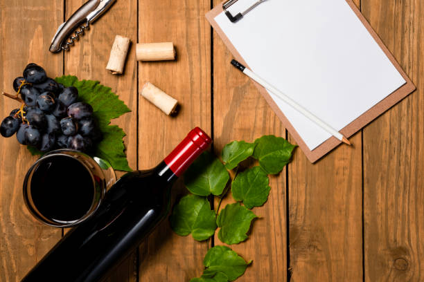 istock Composition with bottle and glass of wine with grape bunch and vine leaves and notepad on wooden background. Top view with copy space 1078146594