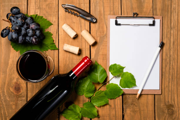 istock Composition with bottle and glass of wine with grape bunch and vine leaves and notepad on wooden background. Top view with copy space 1078146880