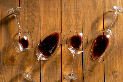 Composition with several used wine glasses with leftover liquid over wooden background. Top view with copy space.