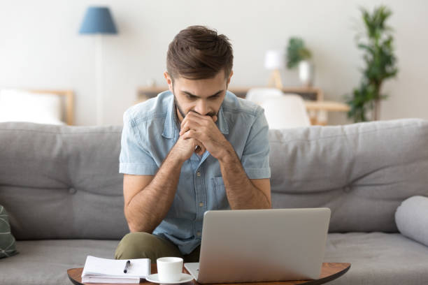 istock Serious male looking at laptop screen thinking 1078149154