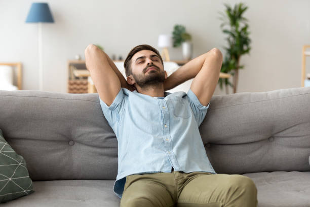 istock Calm man relaxing on sofa hands over head 1078149216