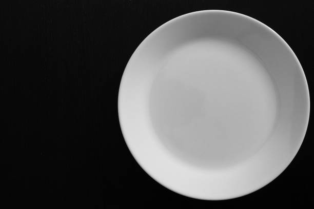 istock Empty white plate on black wooden table 1078152760
