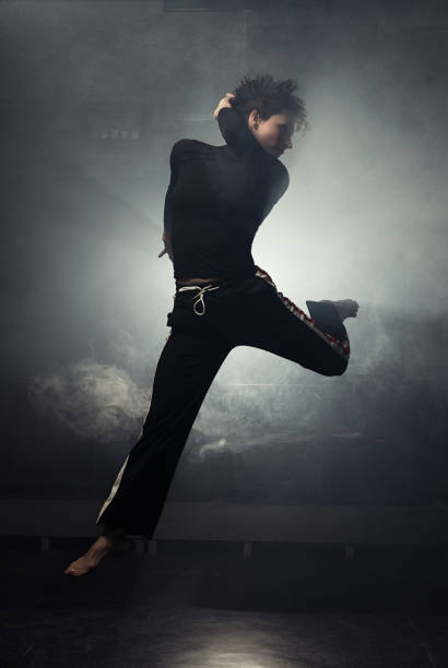 istock modern beautiful dancer in black clothes posing against the Studio in the smoke 1078155676