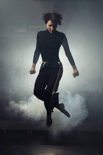 istock modern beautiful dancer in black clothes posing against the Studio in the smoke 1078155750