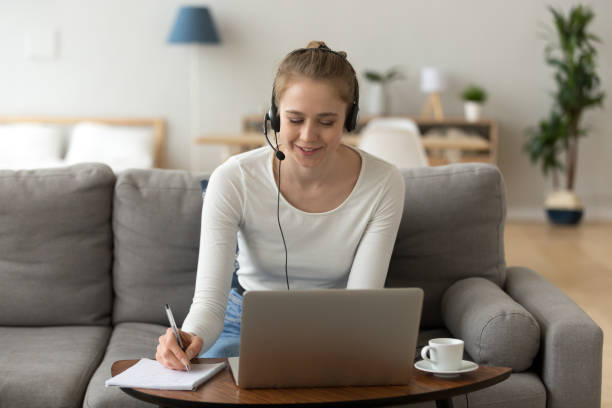 istock Young female in headset working at laptop from home 1078156346