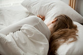 Female sleep on white sheets relaxing in cozy bedroom