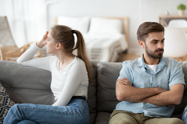 uomo e donna si siedono separatamente sul divano dopo la lotta - back lite foto e immagini stock