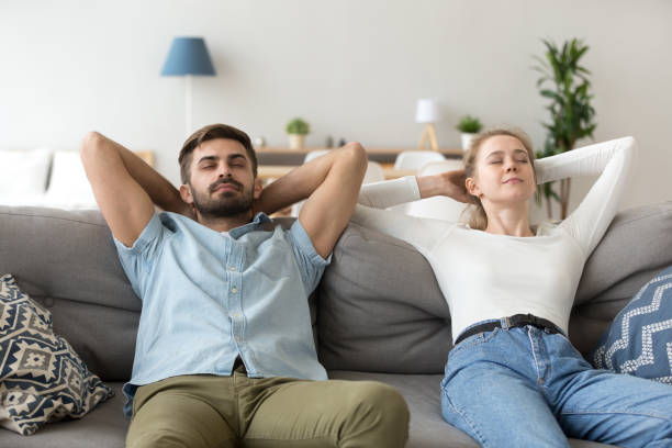 istock Calm husband and wife relax on couch hands over head 1078159384