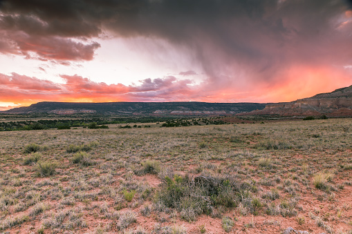 A storm approaches at sunset over the high desert landscape near Abiquiu, New Mexico.