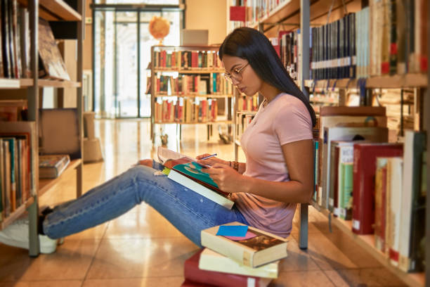 istock woman reading a book in the library 1078176798