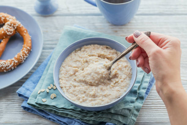 ciotola di porridge di farina d'avena sullo sfondo bianco di legno. - oatmeal heat bowl breakfast foto e immagini stock